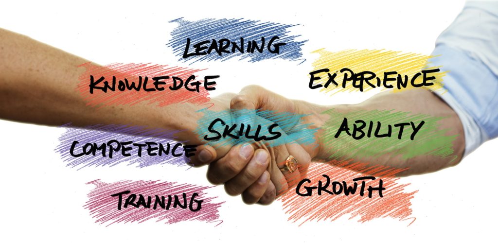 Händedruck mit farbig unterlegten Schlagworten Learning, Skills, Knwoledge, Experience, Ability, Growth, Training, Competence