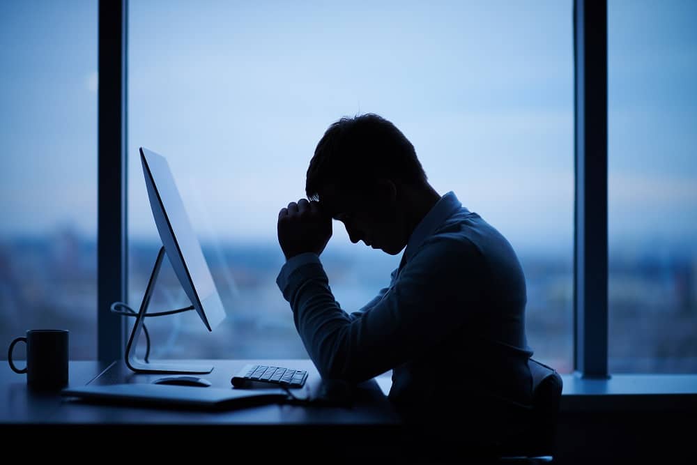 Cyberbullying am Arbeitsplatz Mann sitzt deprimiert vor dem PC